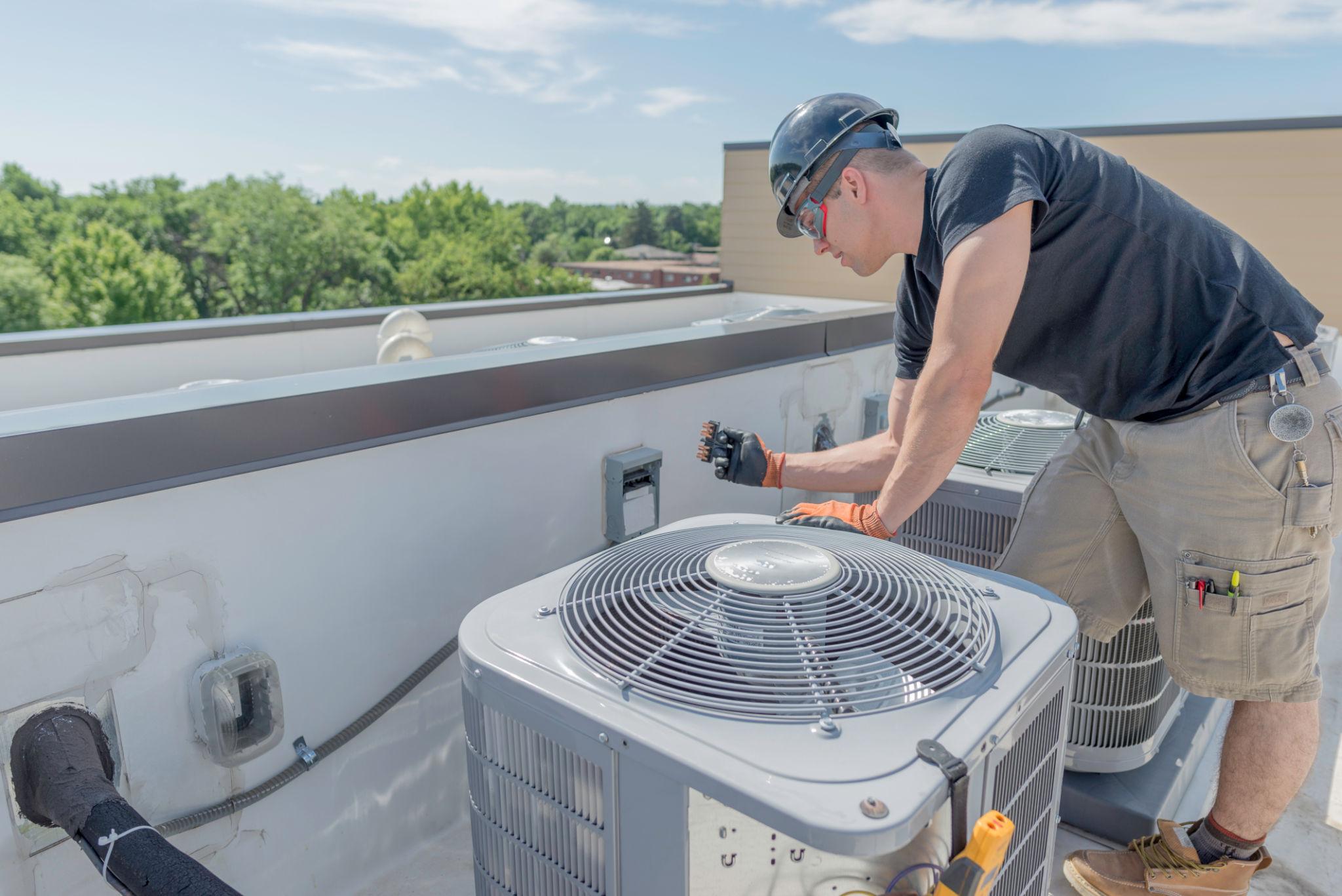 HVAC technician installing a soft-start device on an air conditioner